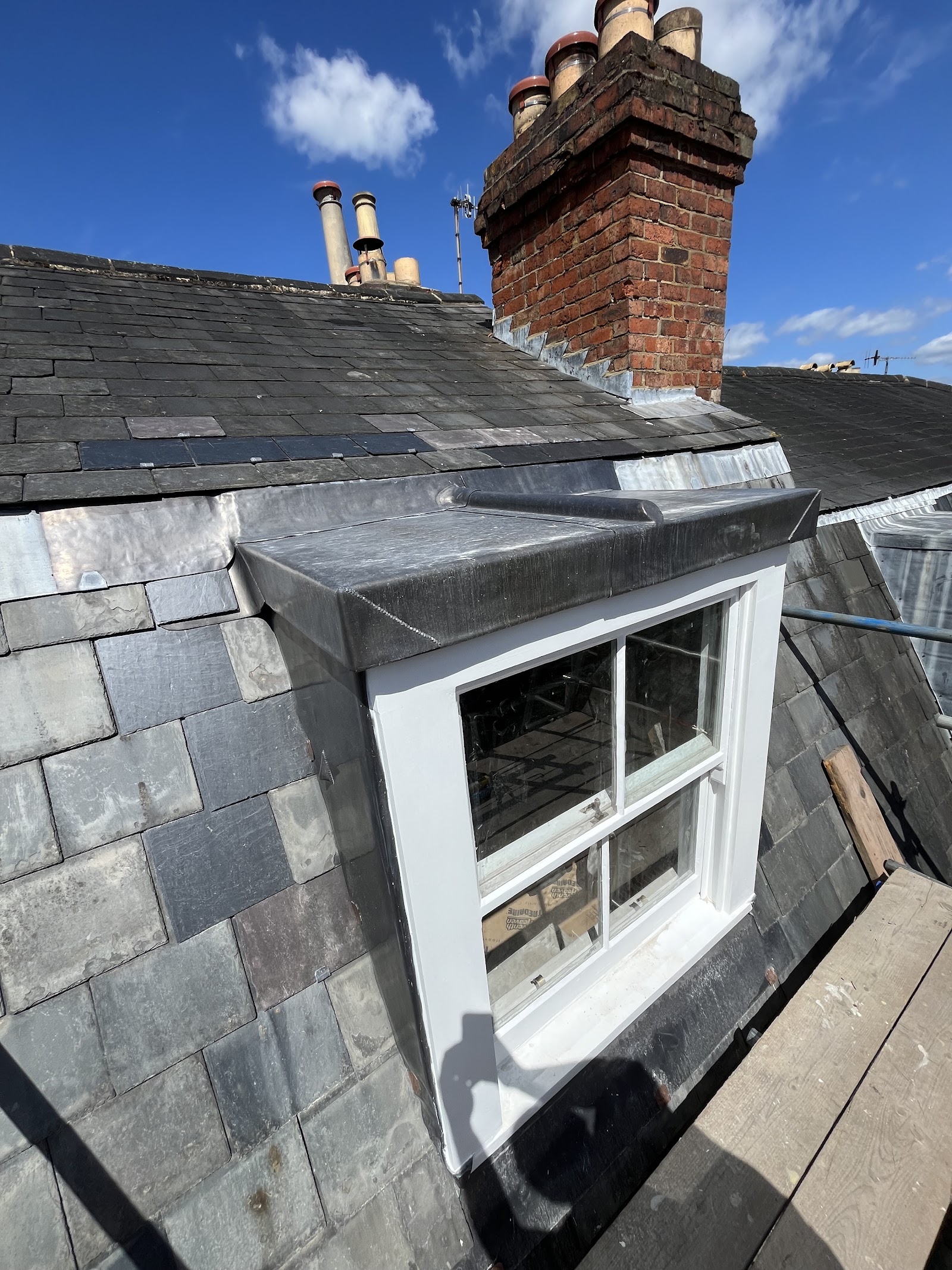 A slate roof and lead-dressed dormer with a traditional sash window.